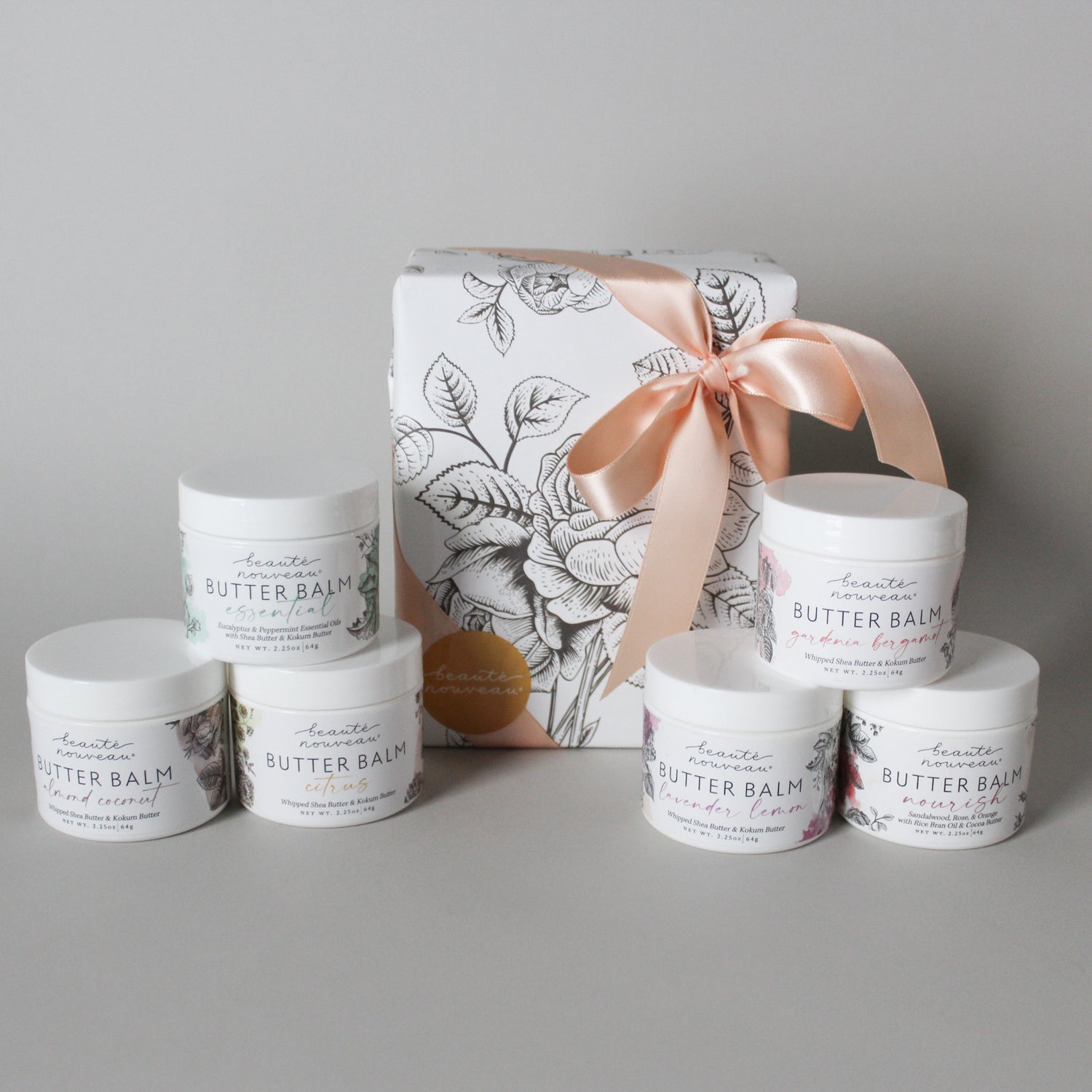 size petite butter balms in white plastic jars with floral labels and a beautifully wrapped package with pink ribbon