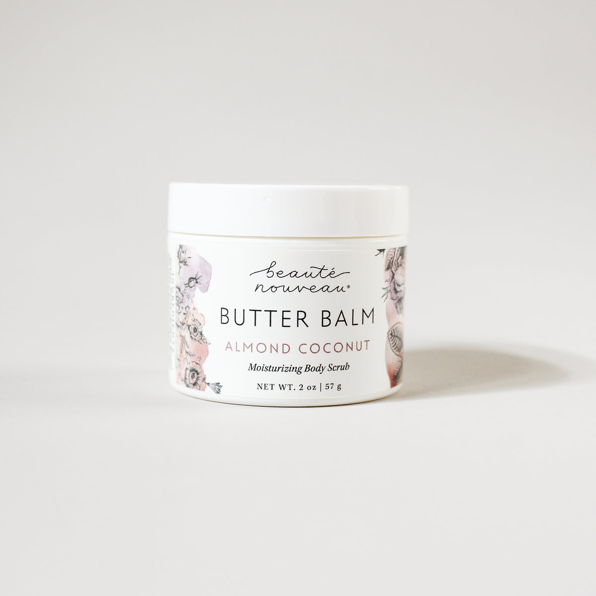 A white plastic jar of Beauté Nouveau Butter Balm in Almond Coconut scent, featuring a white label with delicate pink and green floral illustrations, set against a clean white background.