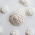A styled flat-lay of Shea Milk Bar Facial Soap showing several sculpted off-white rose-shaped soaps on a white marble surface.